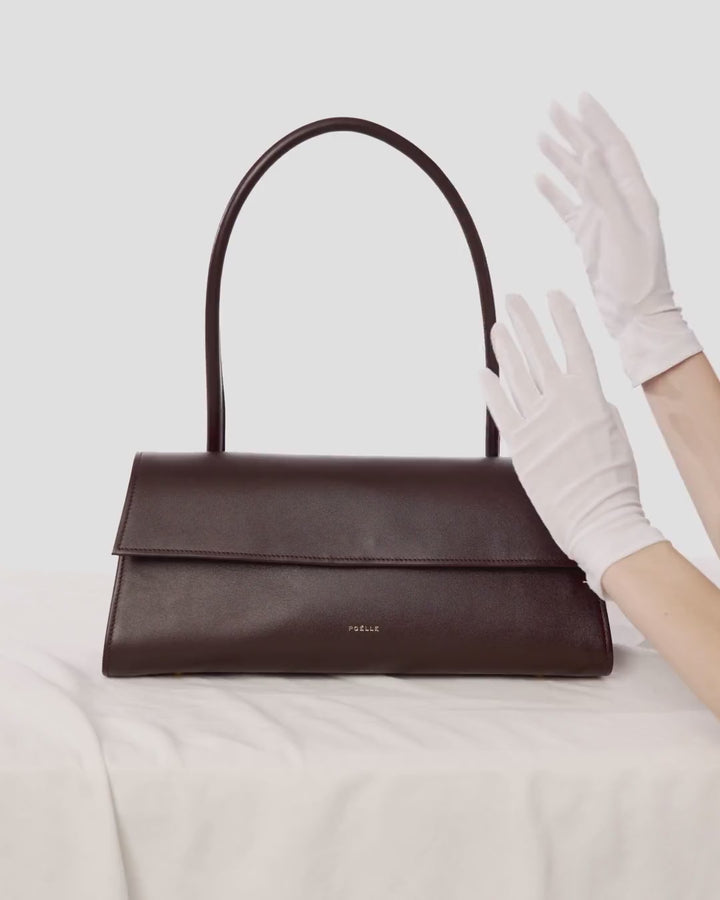 White gloves touching a Poelle bag